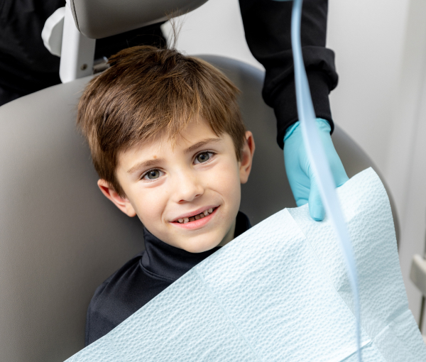 a child smiling as he sits in a dental chair